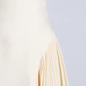 Detail view showing fine pleated skirt and diagonal waist stitching on cream sleeveless dress