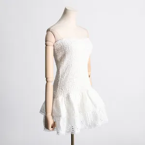Vista de detalle de vestido blanco palabra de honor con bordados y volantes