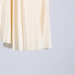 Close-up detail of fine vertical pleats on a cream French-style sleeveless dress.