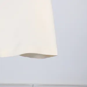 Close-up detail of the clean hemline on a white French style sleeveless pleated dress.