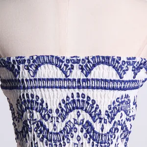 Detalle de primer plano del corpiño nido de abeja bordado en azul de vestido playero blanco