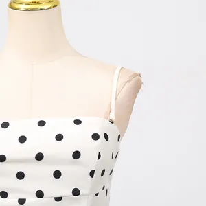 Dettaglio di un elegante abito francese a sottoveste bianco con pois neri stampati