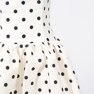 Dettaglio di un abito francese a pois neri con eleganti pieghe in vita e tessuto di qualità