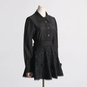 Vista detallada de una elegante blusa negra con bordes festoneados y falda de encaje
