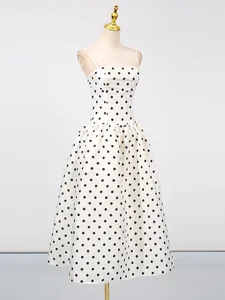 Elegante abito bianco a spalline in stile francese con stampa a pois neri e vita segnata.