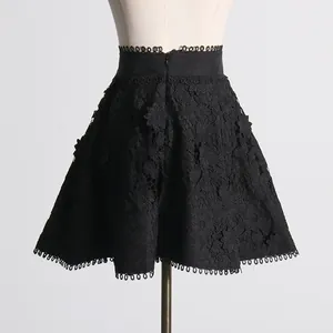 Vista detallada de minifalda de encaje floral negro con borde de flecos decorativos.