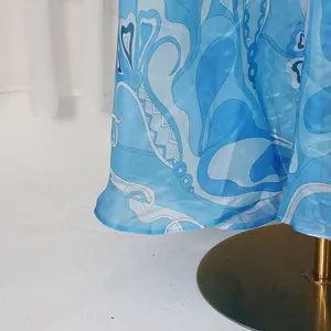 Close-up detail of a blue retro printed satin skirt showing the irregular hem and texture.