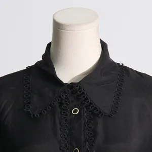 Vista detallada de un cuello de camisa negra elegante con delicados bordes de borlas