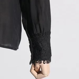 Detalle de la manga de una camisa negra con elegantes puños de encaje y botones.