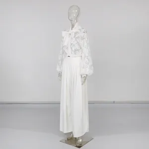Vista laterale del set camicia in pizzo bianco con fiocco e pantaloni larghi a pieghe