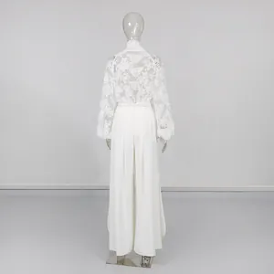 Vista posteriore di completo con top in pizzo bianco e pantaloni larghi a fessura