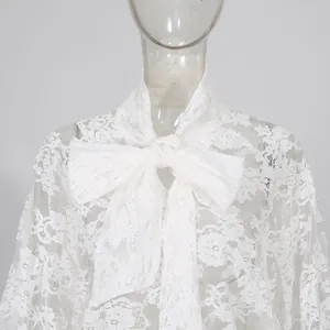 Dettaglio ravvicinato dell'elegante top in pizzo bianco con grande fiocco sullo scollo