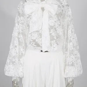 Dettaglio camicetta pizzo bianco con fiocco e pantaloni larghi con spacco a vita alta