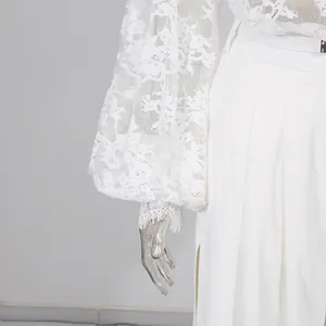 Vista dettagliata della manica in pizzo bianco e dei pantaloni a gamba larga con spacco alto