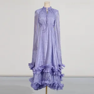Vestido largo morado elegante con mangas de capa, tela brillante y bajo de volantes.