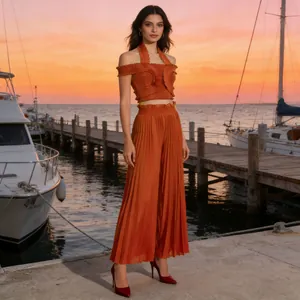 Burnt orange pleated two-piece set featuring halter ruffle top and high waist pants