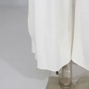 Dettaglio dell'orlo dei pantaloni bianchi a gamba larga con spacco laterale e tessuto fluido