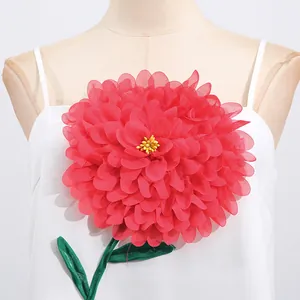 Detailansicht einer großen roten stereoskopischen Stoffblume auf weißem Kleid.
