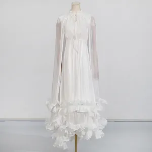 Detalle de un vestido largo blanco de lujo estilo capa con volantes elegantes bordados