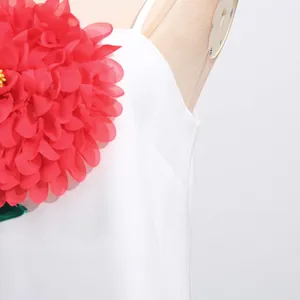Detailaufnahme einer großen roten 3D-Organzablume auf einem weißen Sommer-Trägerkleid.