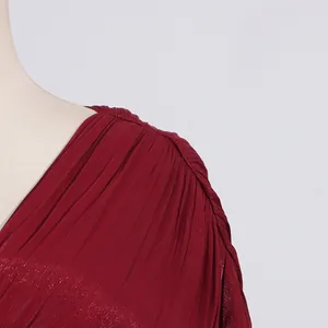 Detailaufnahme der plissierten Schulter an einem schimmernden weinroten Satinkleid