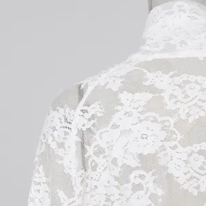 Dettaglio ravvicinato della trama in pizzo floreale bianco dell'elegante top estivo