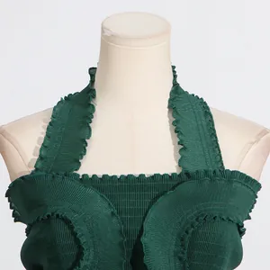 Detailed view of green pleated halter top featuring ruffle edge and smocked texture.