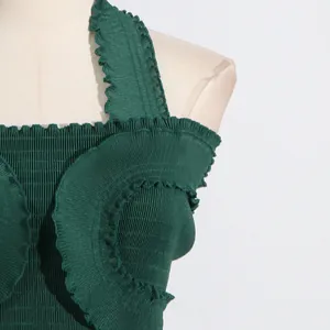 Close-up of dark green pleated halter top featuring elegant ruffled details on smocked fabric.