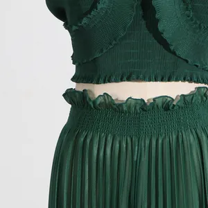 Detail shot of a dark green pleated set featuring ruffle edges and textured fabric