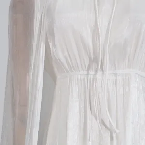 Primer plano de un vestido de capa blanco brillante que muestra la textura plisada de la tela.