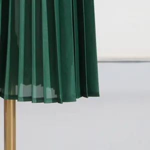 Close-up of dark green pleated fabric showing high-quality texture and fine pleats.