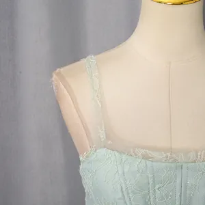Detail view of light green lace embroidery and mesh straps on a bridesmaid dress