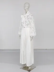 Completo elegante con camicetta di pizzo con fiocco e pantaloni larghi bianchi