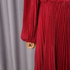 Close-up of red pleated dress featuring metallic shimmer fabric and lantern sleeve cuff
