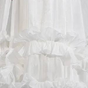 Detalle de los bordes de volantes blancos multicapa en un vestido de noche brillante.