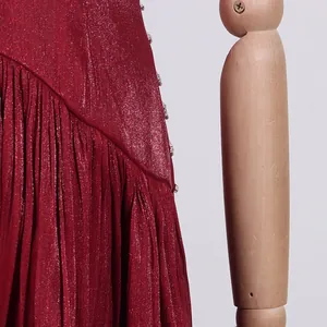 Nahaufnahme eines burgunderroten Faltenkleides aus Satin mit feinem Glitzer und Strass.