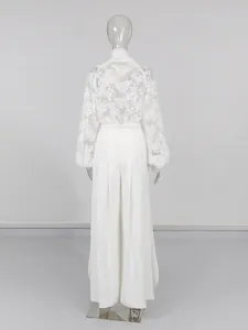 Elegante set top in pizzo bianco e pantaloni larghi, raffinata vista posteriore