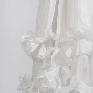 Primer plano detallado de un vestido blanco elegante con bordes de volantes y tela lustrosa