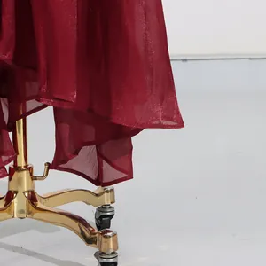 Detailansicht eines burgunderfarbenen Faltenkleid-Saums mit schimmerndem Stoff.