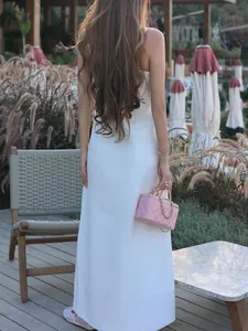 Elegante abito lungo bianco con spalline sottili e fiori 3D, vista posteriore all'aperto