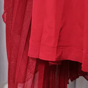 Detailed view of red pleated chiffon dress fabric featuring elegant metallic shimmer effect