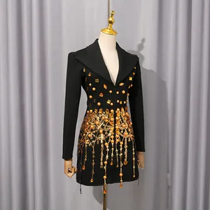Detail view of luxurious gold sequins and fringe tassels on a black blazer dress