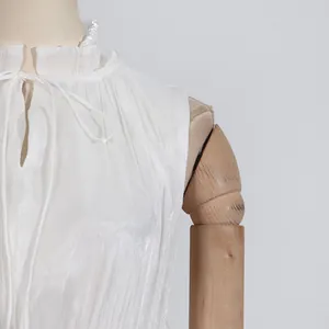Detalle de primer plano de un vestido blanco con cuello de volantes y elegante lazo