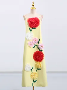 Elegante abito lungo giallo con vivaci applicazioni floreali 3D su un manichino da sarta.