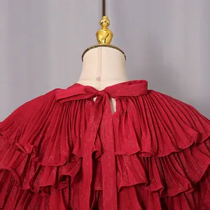 Close-up detail of a red pleated chiffon dress with a tie-neck bow and tiered ruffles