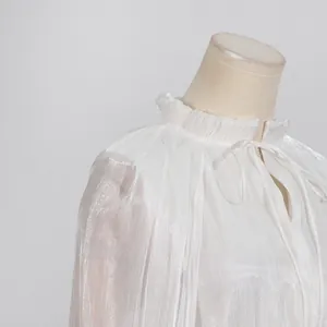 Primer plano del cuello con volantes blancos y el tejido brillante de un vestido de gala.