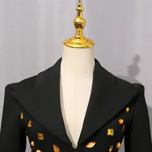 Close-up detail view of black suit dress featuring vintage orange gemstone embellishments