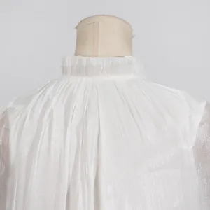 Primer plano del cuello con volantes plisados en vestido de gala blanco de lujo con brillo