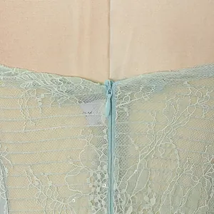Close-up detail of delicate mint green lace embroidery and invisible back zipper on dress