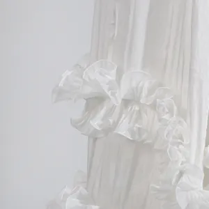 Detalle de cerca que muestra la tela blanca brillante con bordes de volantes de un vestido.